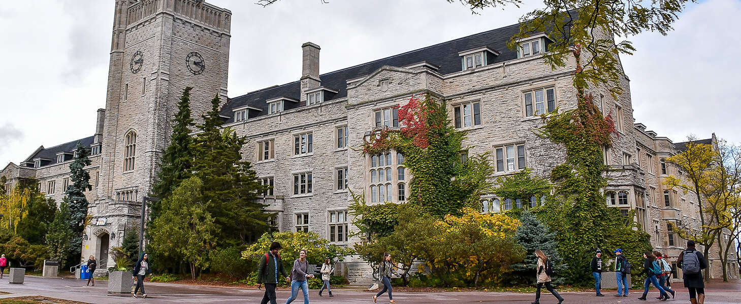 Students walk by Johnston Hall on a partly-cloudy day.