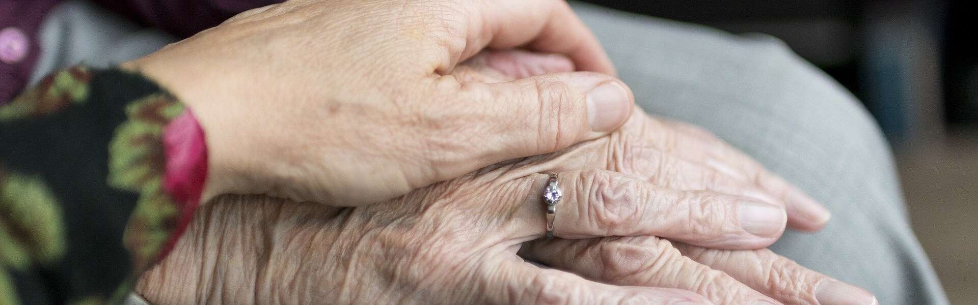 A senior puts their hand onto the hands of another senior