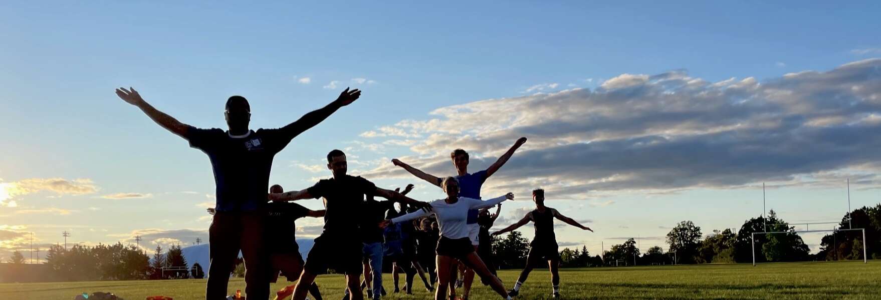 About 10 people stretching on an athletic field