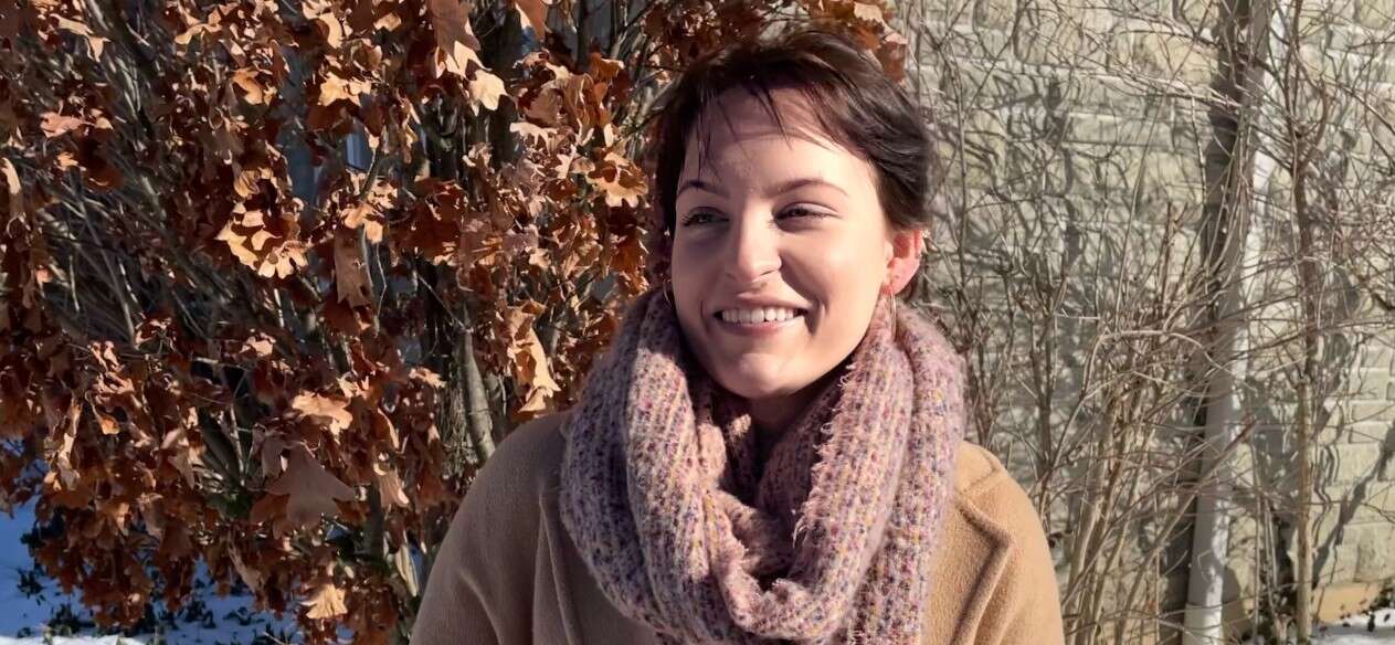 Emma Hak-Kovacs stands amid snow and smiles looking off-camera
