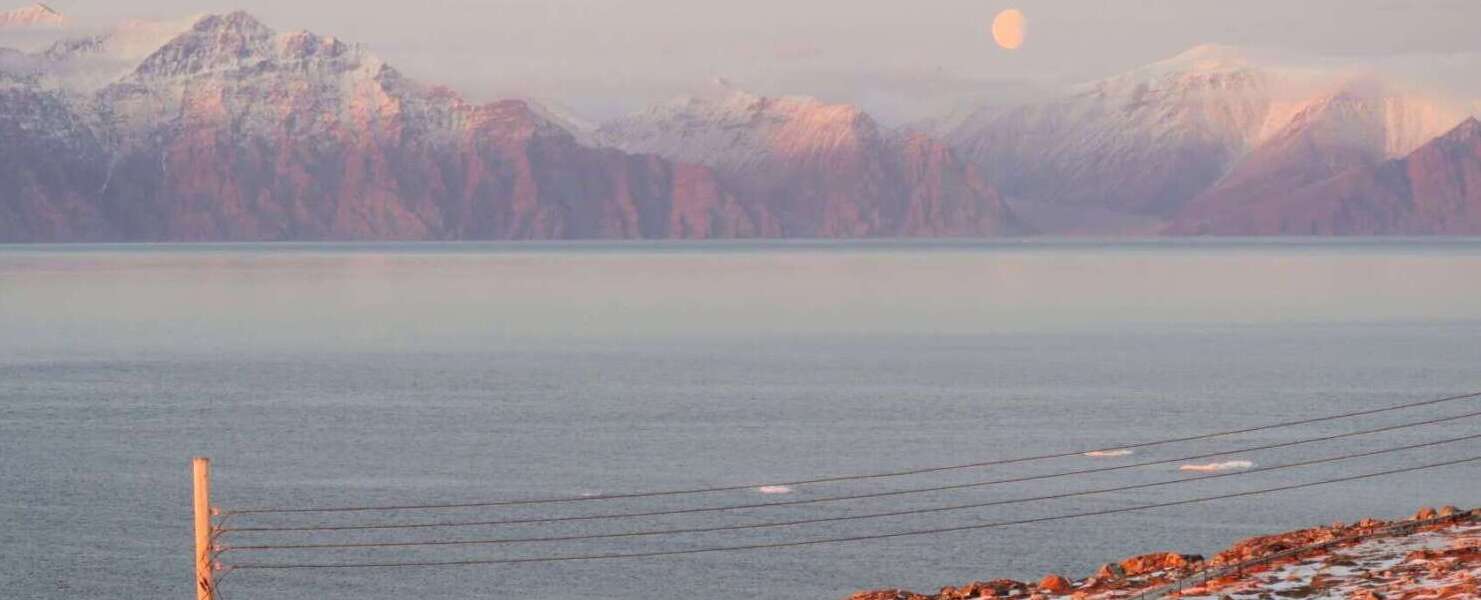 Landscape photo of the sun setting over Pond Inlet (Mittimatalik)