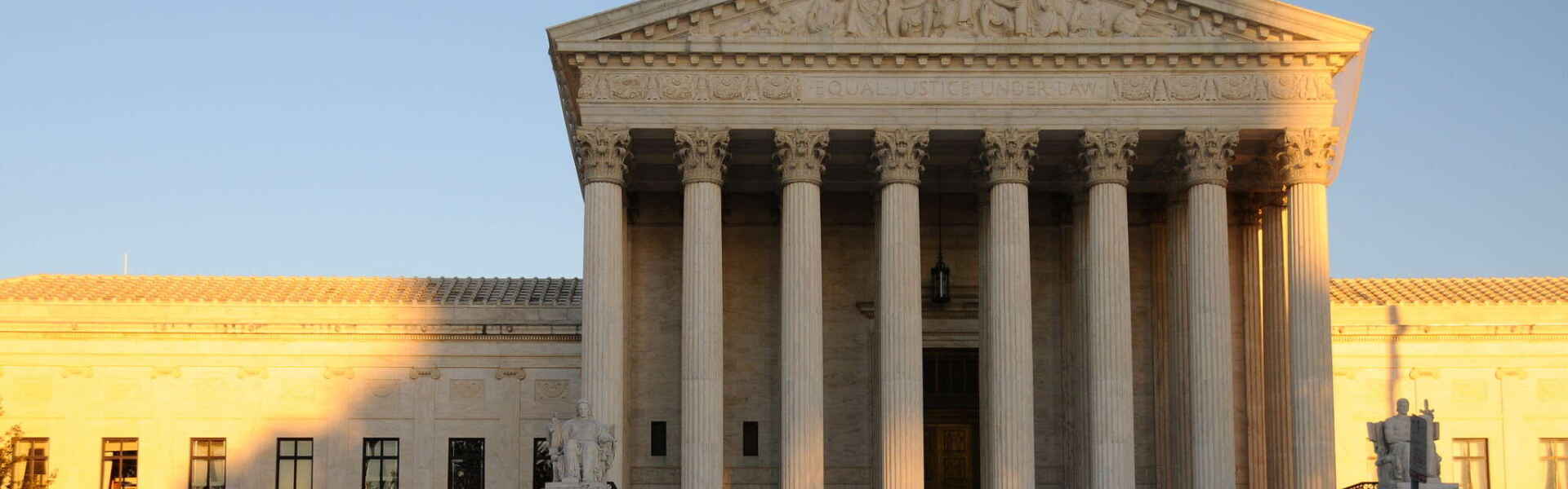 The U.S. Supreme Court, a white pillared building, at sunset.