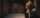 A person leaning against a wall in dim hallway