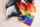 Two people sit with Progress Pride flag draped over them.