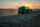 Farm equipmentstirs up dust on a field during sunset
