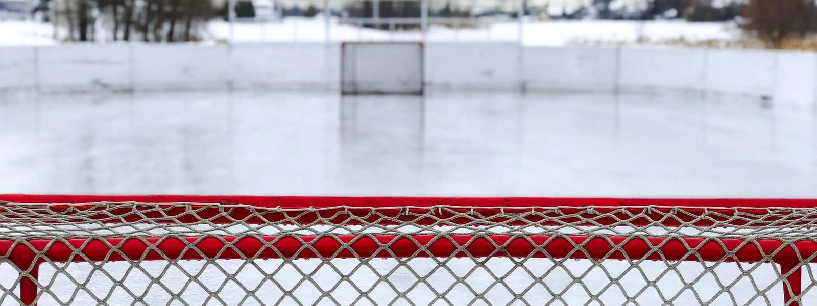 A red and white goal net on ice field