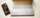 A phone set to its homescreen sits next to an open laptop on a table.