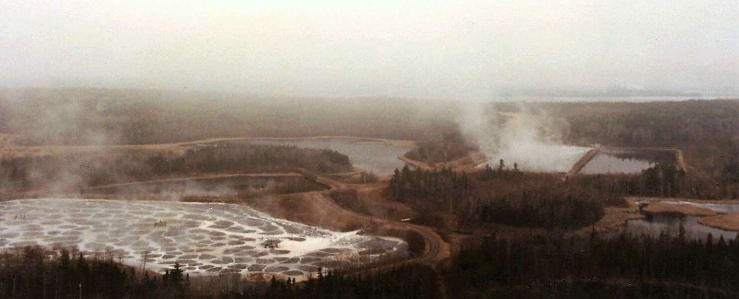 A sepia-toned overhead photo of a pulp mill and reservoirs filled with waste