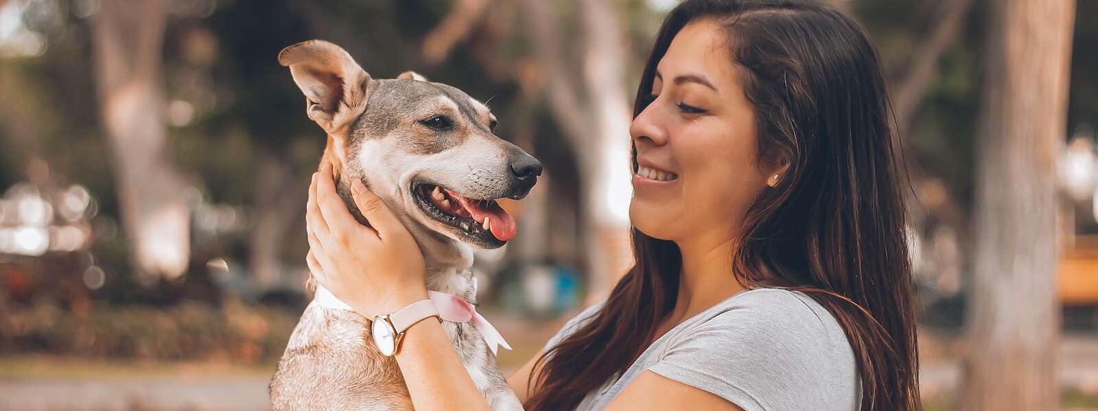 A woman holds their dog in a park