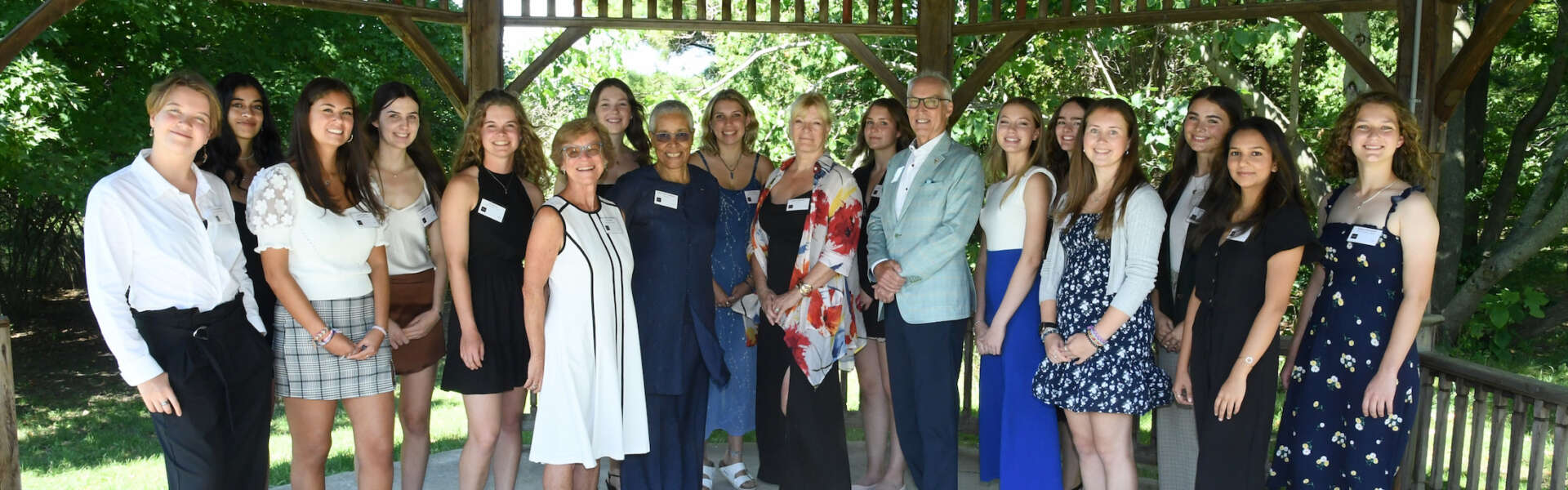 Seventeen people stand in two rows in a gazebo