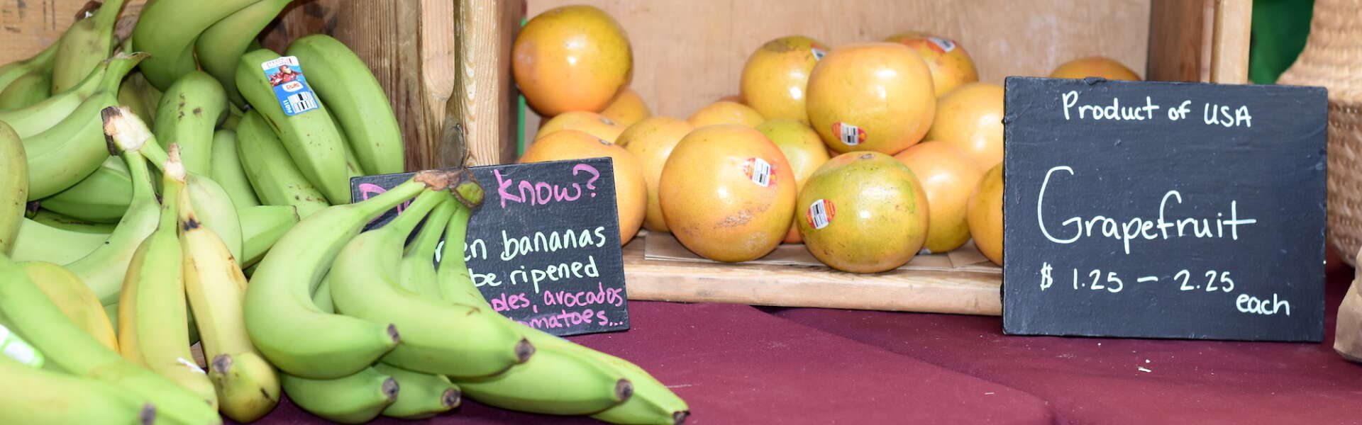 Crates of bananas and grapefruit sit on a tablecoth-covered table