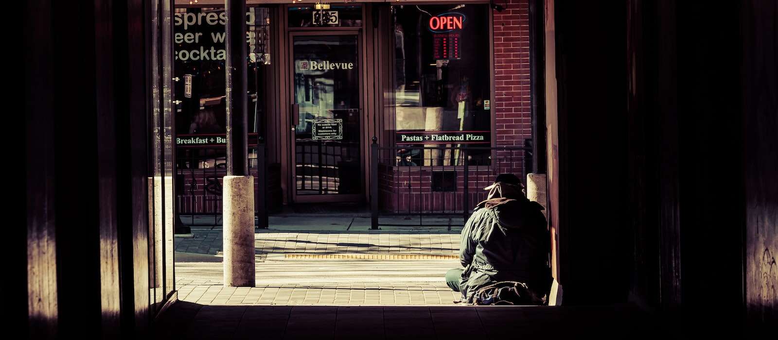 A person sits at the top of a set of stairs in an urban area.