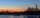 Parliament Hill and the Ottawa skyline are silhouetted at sunrise behind the Rideau River