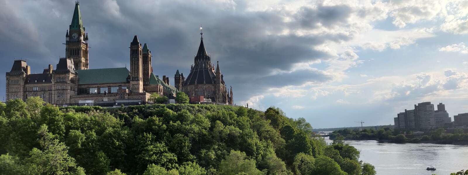 Parliament building overlooking the Ottawa River under white clouds