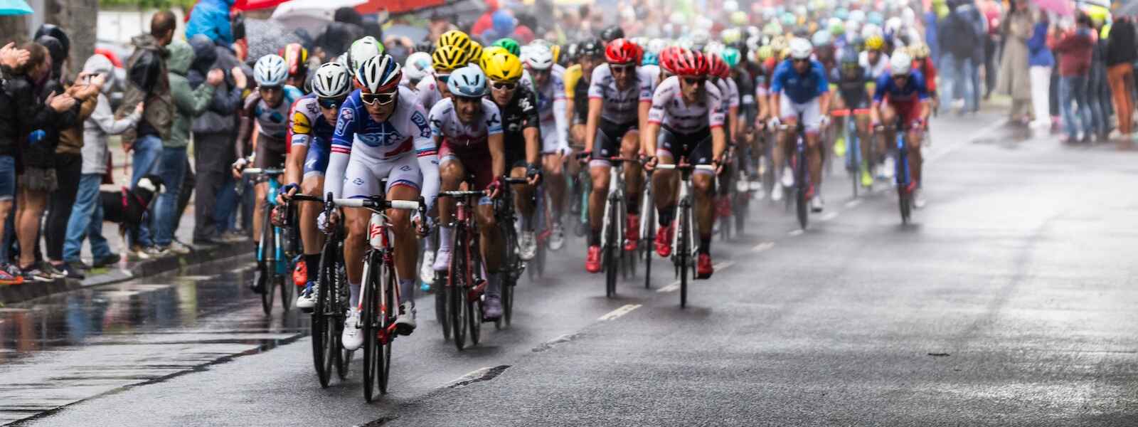 People riding bicycles in a road race during a sun shower