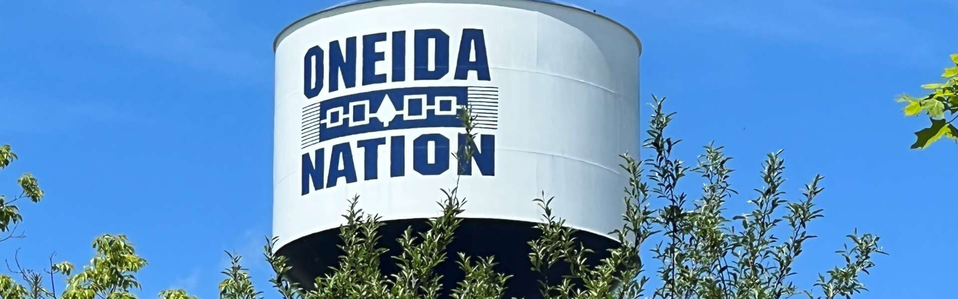 a water tower with the words oneida nation sits above a stand of trees