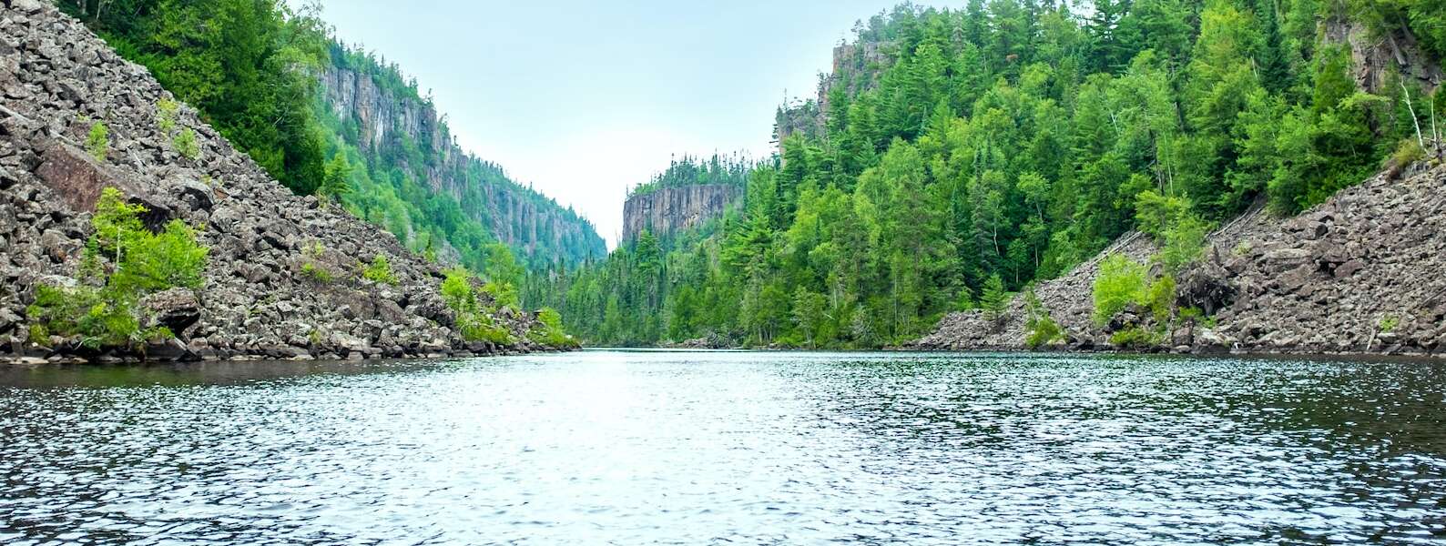 a wide river with conifer-covered cliffs on either side