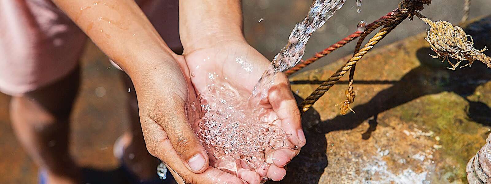 outstretched hands gather water from a water pump