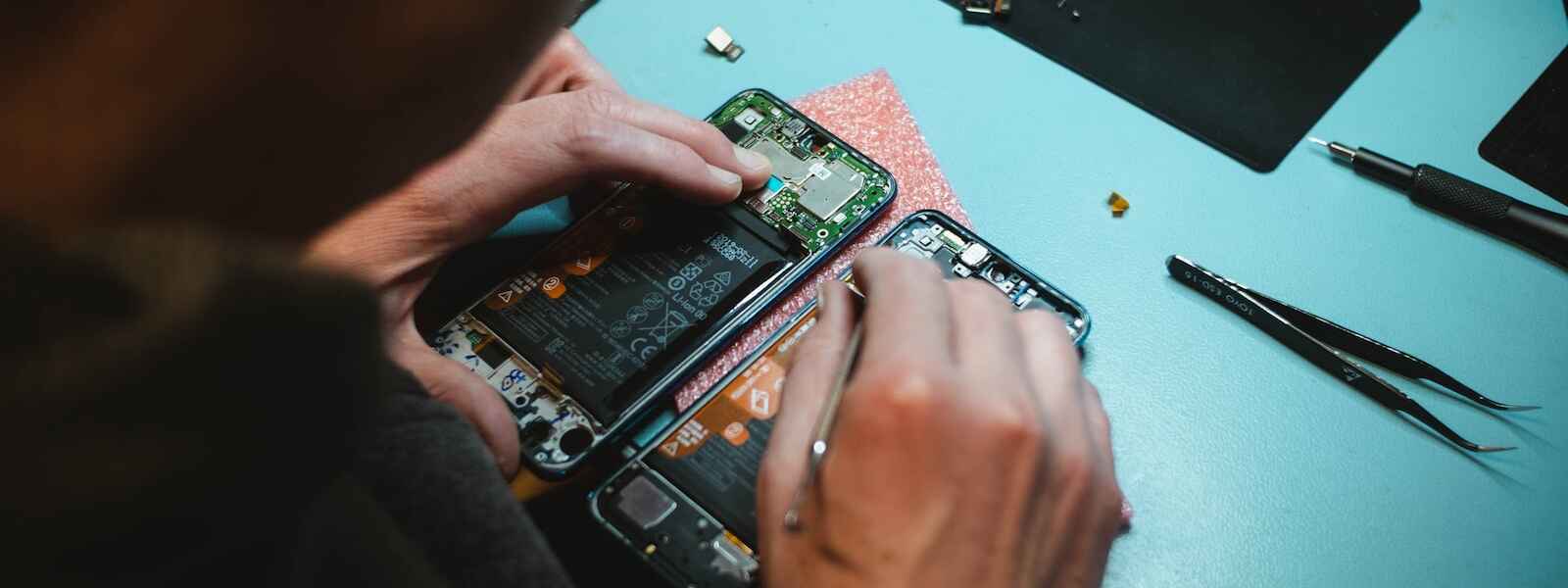 person repairing smartphones under a lighted table