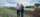 Two people stand in a field on a sunny day and inspect green onionsamples from a test polt