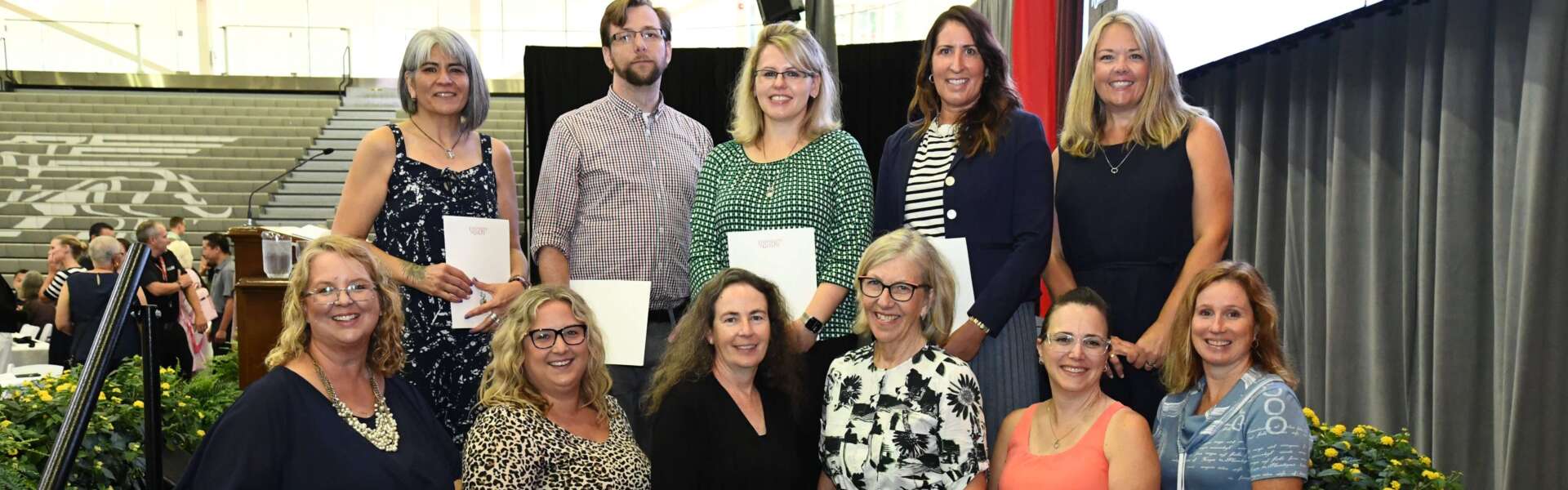 Two rows of U of G staff members stand together with President Dr. Charlotte Yates holding their exemplary staff awards.