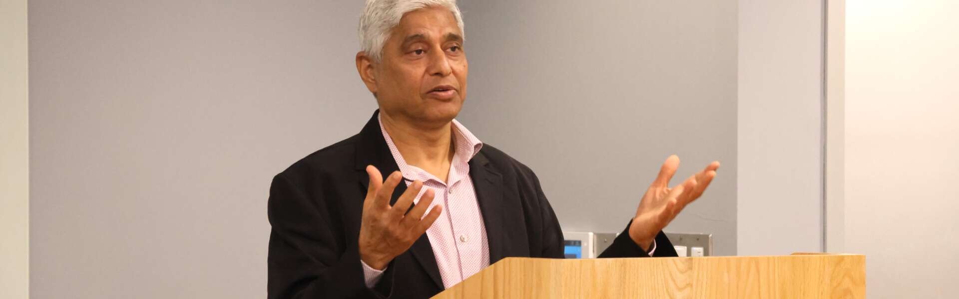 a man gestures with his hands while standing at a podium marked University of Guelph