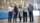 Five people pose for a photo standing in a large dairy barn