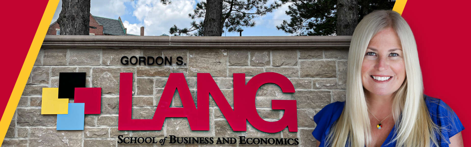 Dr. Sara Mann in front of the Gordon S. Lang School of Business and Economics brick wall sign.
