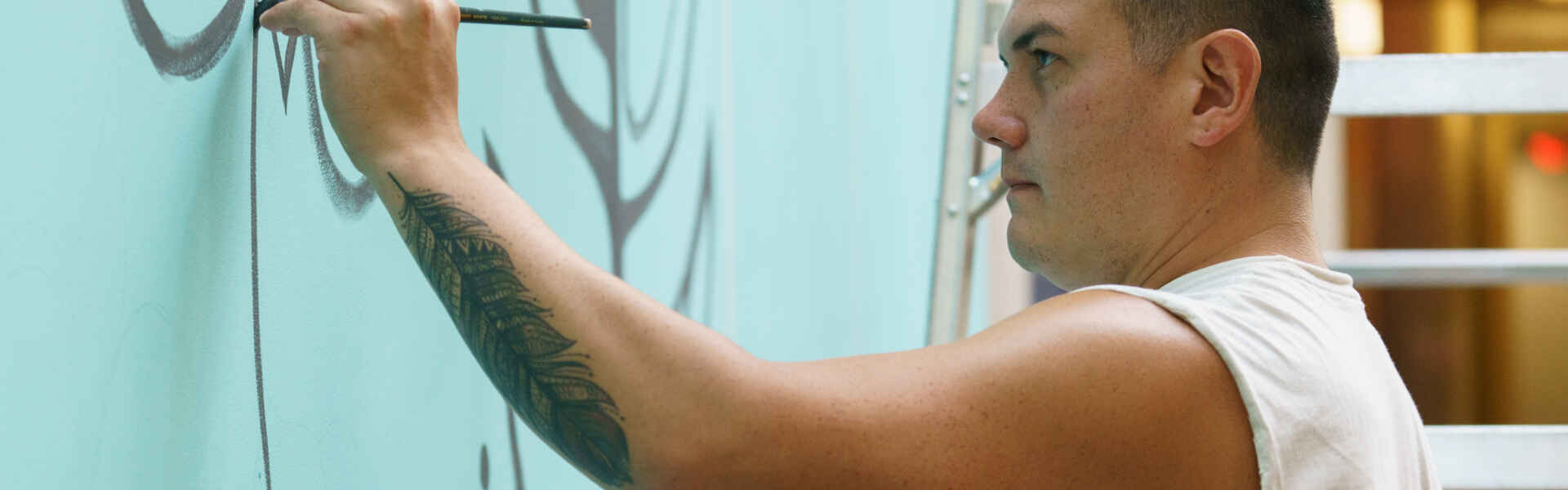 A man paints a mural on a wall.
