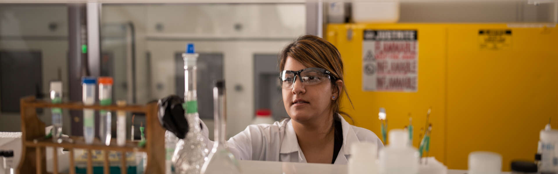 A woman wearing a lab coat works in a lab.