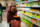 In a grocery store, beside a shelf full of items, a person hunches down to grab something out of their bag.