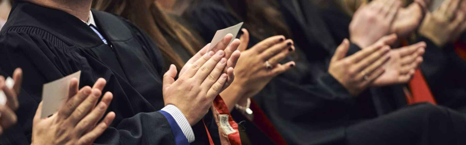 A zoomed-in shot of a row of hands clapping at a convocation ceremony