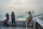 Three students on a boat, with two observing the water and one pointing towards the horizon. The scene is misty, with a calm sea stretching out in front of them.
