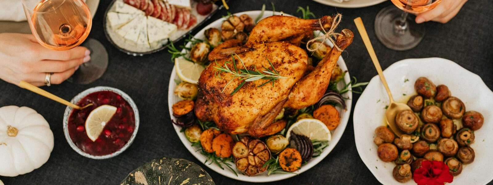 A delicious Thanksgiving feast featuring roasted chicken, wine, and seasonal sides. Top view.
