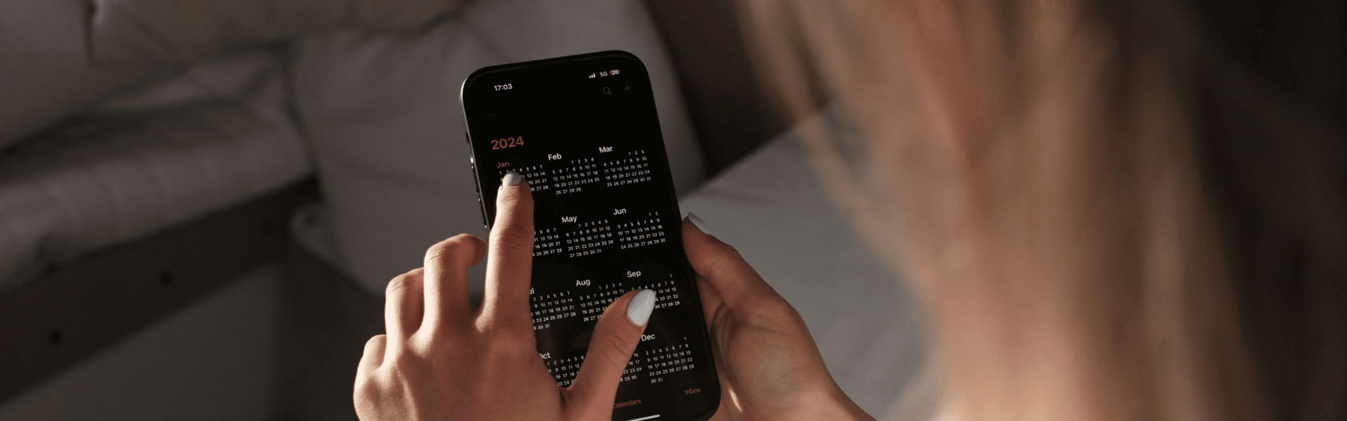Over the shoulder shot of a person pointing to their calendar on a smartphone