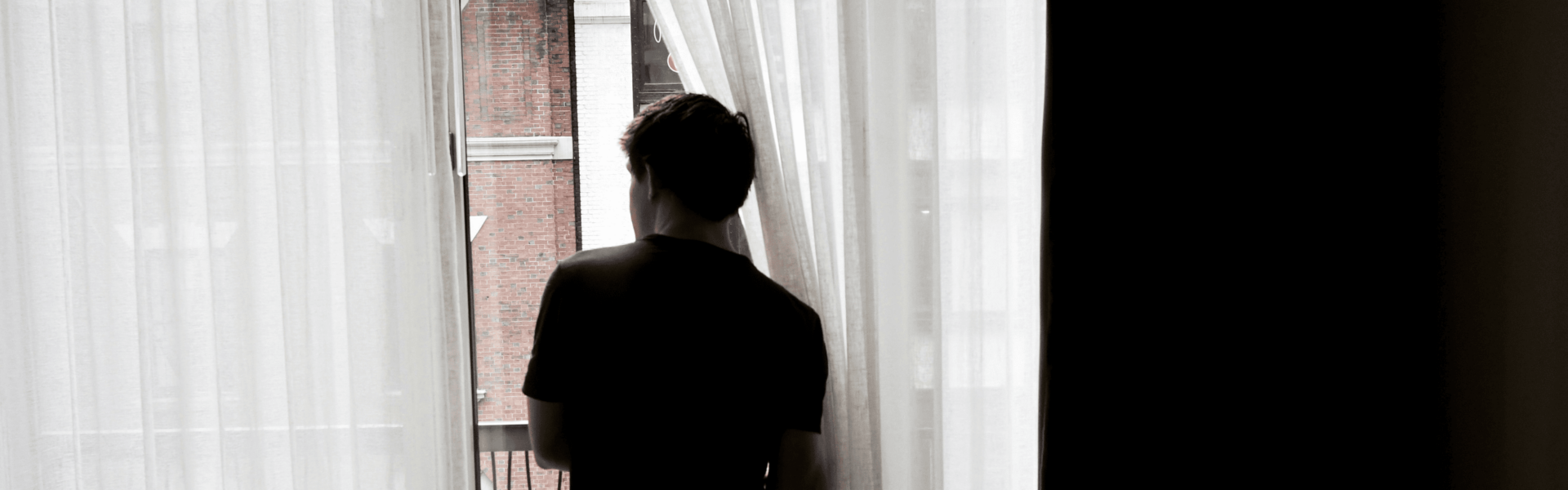 Silhouette of a person looking out of a window