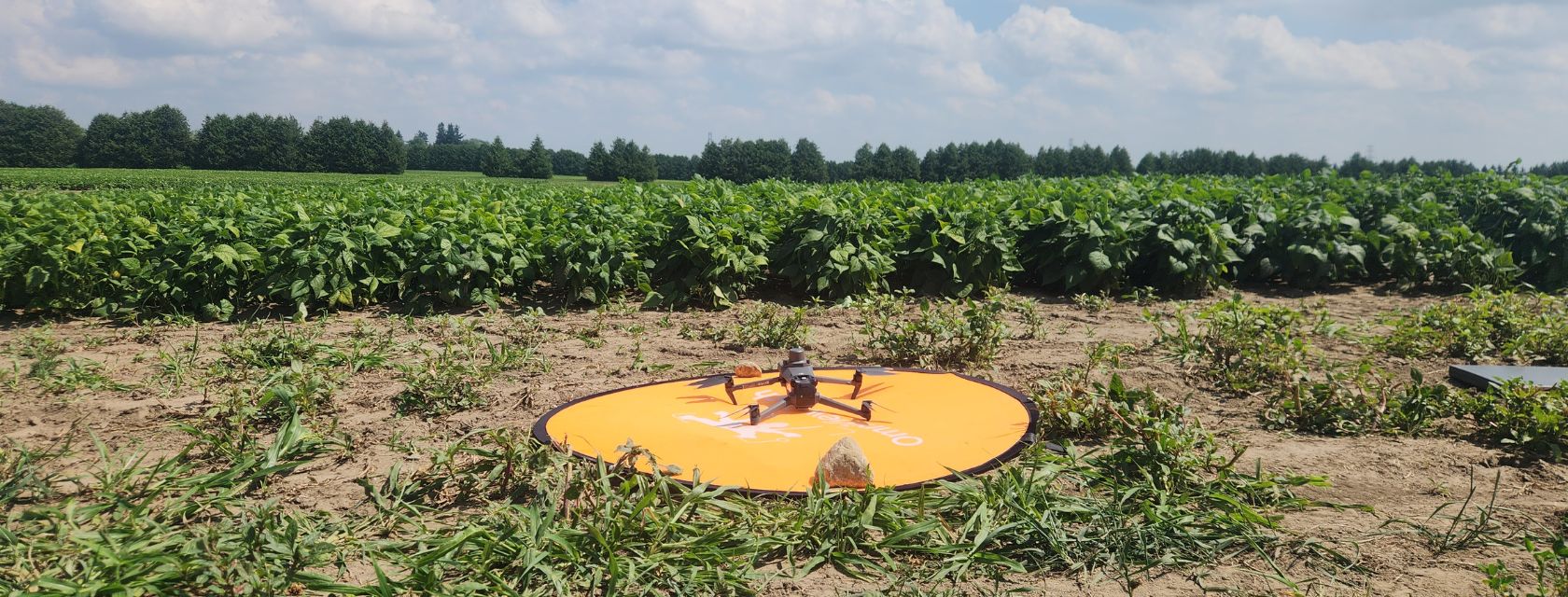 drone with four legs on a launch pad in front of a field