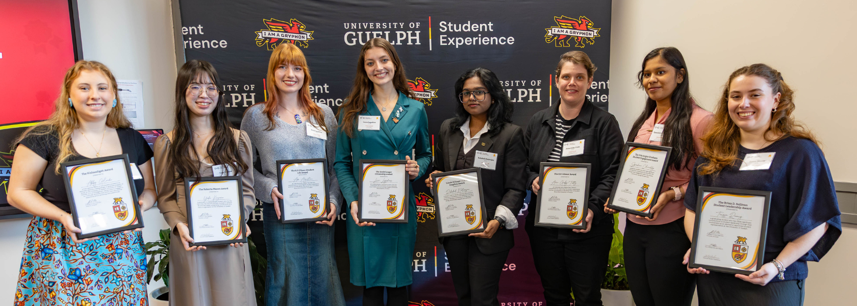 The student experience award winners stand in a line, each holding their award certificate and smiling.