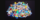 A pile of colourful microplastics sits on a black background.
