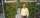 person in button shirt stands in front of green plants on a wall